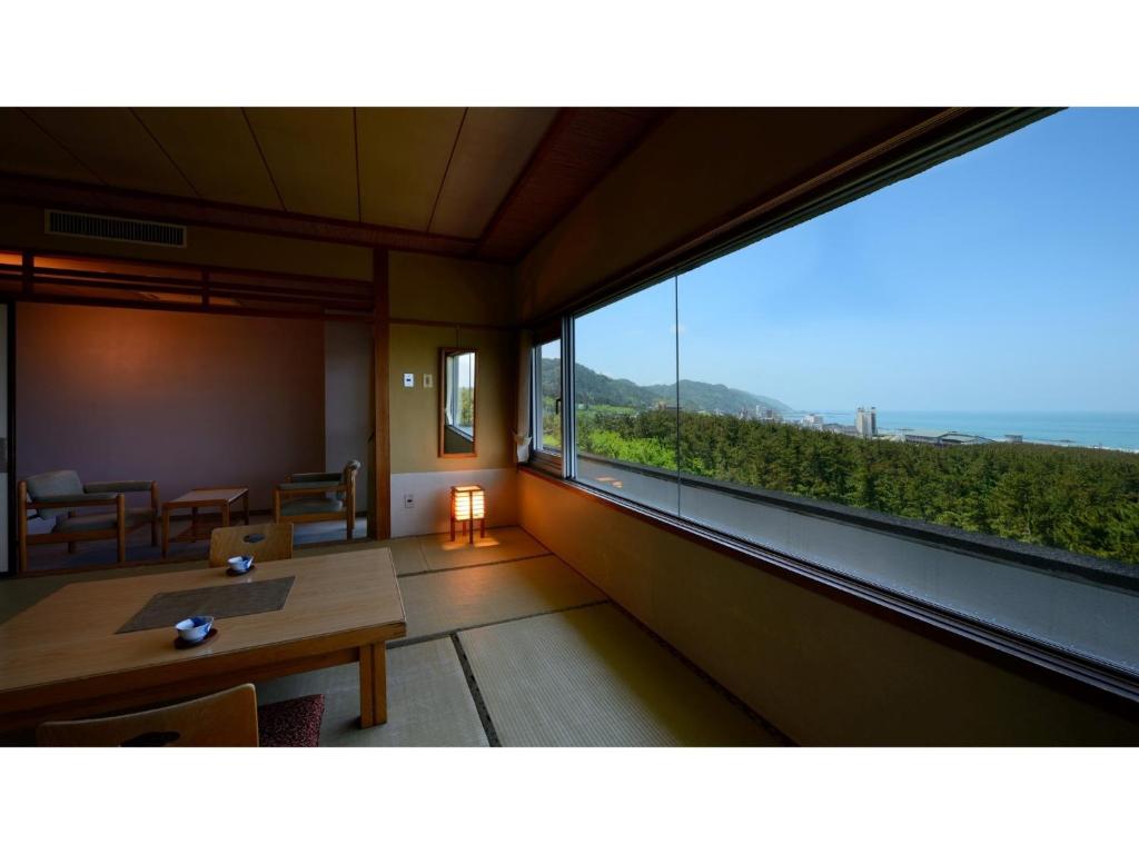 鹤冈市Yunohama Onsen Hanayubi Nihonkai - Vacation STAY 67572v的客房设有桌子和大窗户。