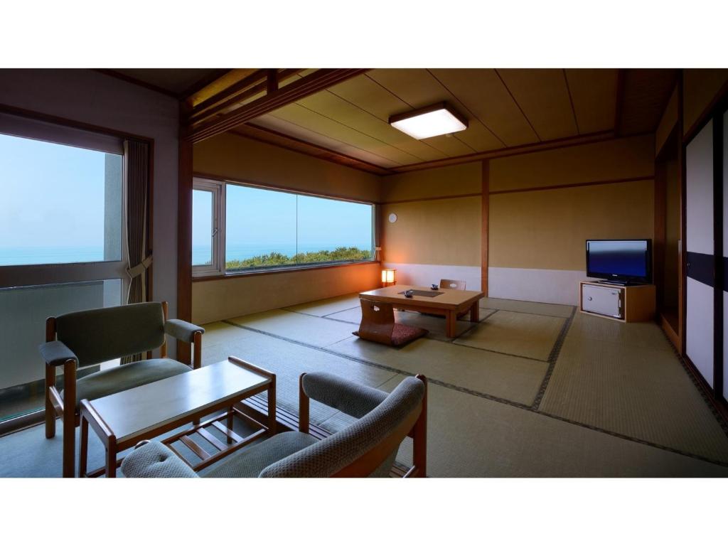 鹤冈市Yunohama Onsen Hanayubi Nihonkai - Vacation STAY 67567v的客厅配有桌椅和电视。