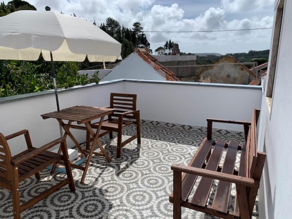 辛特拉Andar tranquilo entre Lisboa Sintra的阳台配有桌椅和遮阳伞。