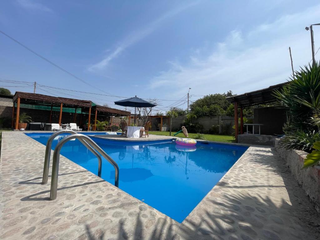 利马Casa en San Fernando Pachacamac的蓝色海水游泳池和遮阳伞