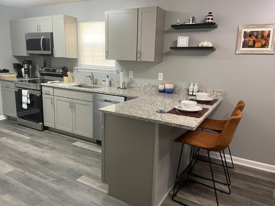 查塔努加Downtown Home in Chattanooga的厨房配有白色橱柜和带凳子的台面