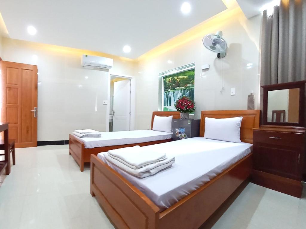 Dĩ AnKHÁCH SẠN CÚC PHƯƠNG (CÚC PHƯƠNG HOTEL)的一间卧室配有两张床和镜子