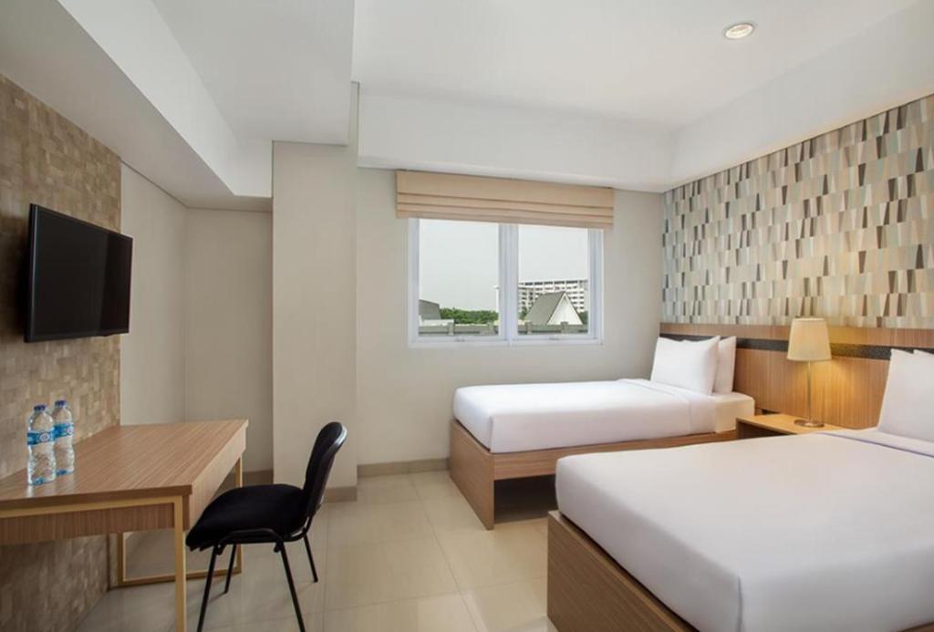 塞尔蓬All Nite and Day Hotel Alam Sutera的酒店客房配有两张床和一张书桌