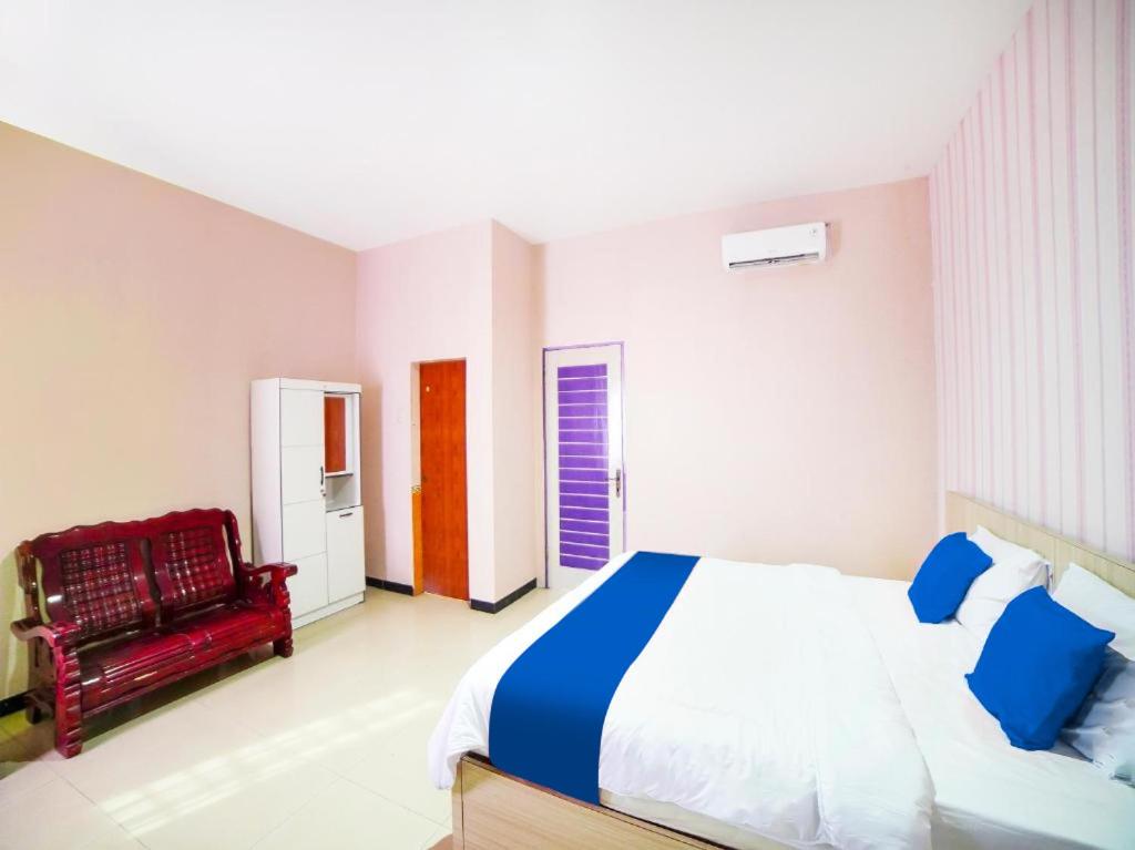 棉兰Sg Premium Guest House By Helocus的一间卧室配有一张大床和一张红色椅子