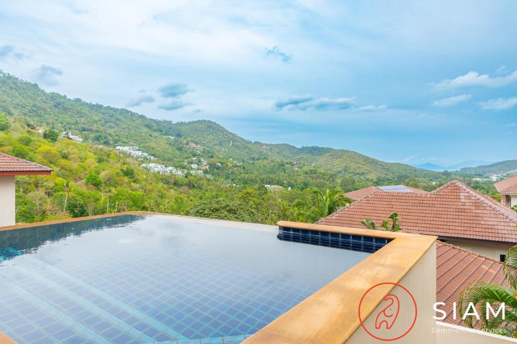 苏梅岛Chaweng Hill Apartment 2Br & Private Pool的一座位于别墅内的游泳池,别墅的背景是群山