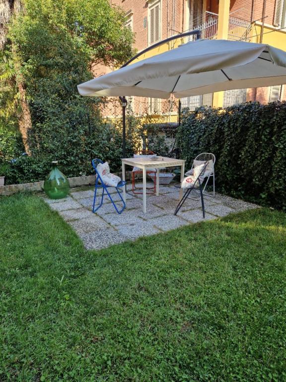 博洛尼亚Minimal Chic House的院子里的一张桌子和两把椅子以及一把雨伞