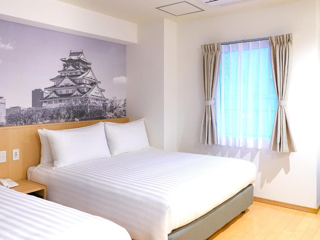 大阪Travelodge Honmachi Osaka的一间卧室设有两张床和窗户。
