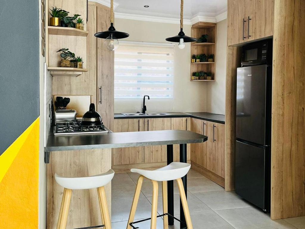 塞昆达Tshepang Apartments Secunda的厨房配有木制橱柜和黑色冰箱。