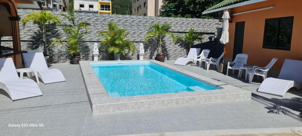 卡伦海滩卡隆之家度假屋的一个带白色躺椅的游泳池和一个庭院