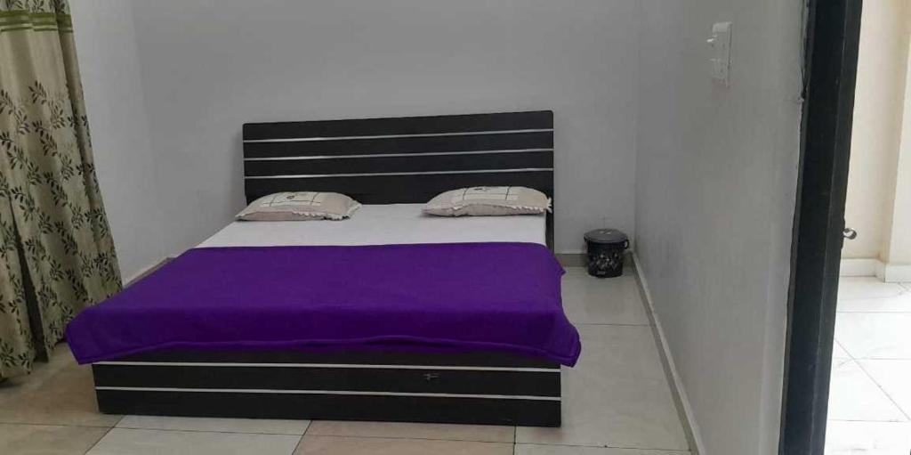 勒克瑙OYO Flagship Tirupati Lawn And Hotel的一间卧室配有一张带紫色毯子的床