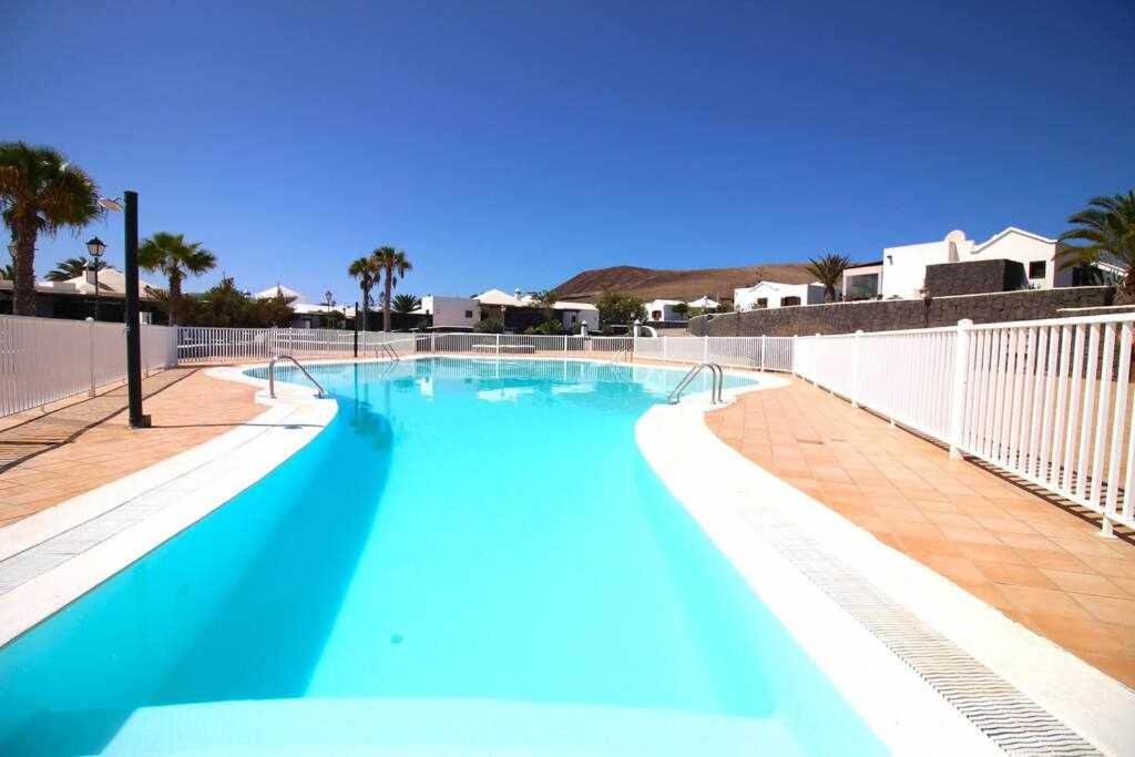 普拉亚布兰卡Cotton House的蓝色的游泳池,拥有白色的围栏和棕榈树