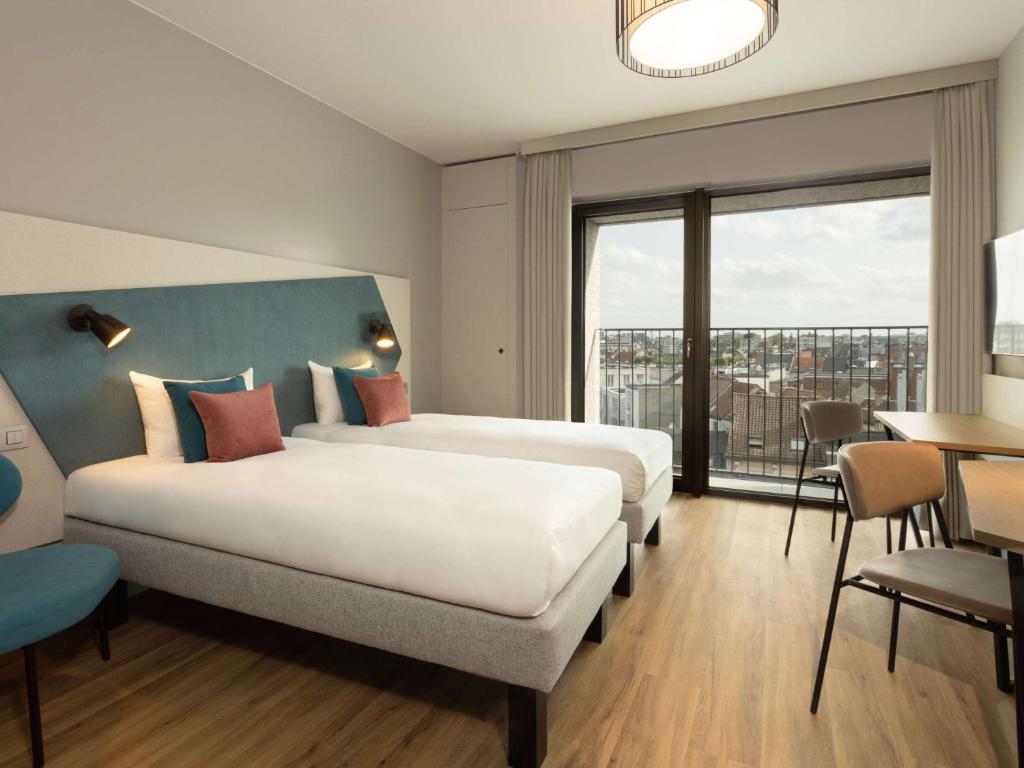 安特卫普Aparthotel Adagio Antwerp City Center的酒店客房设有两张床和大窗户。