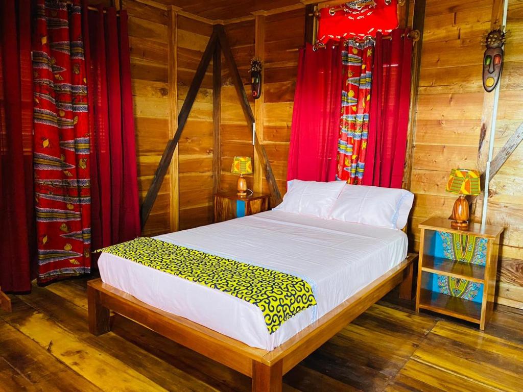 M. PeixeMonte Mar SãoTomé的木墙和红色窗帘的客房内的一张床位