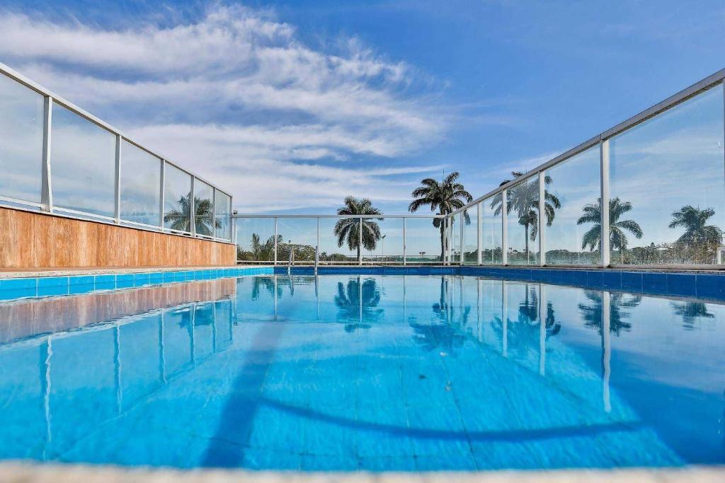贝洛奥里藏特Hotel San Diego Pampulha - Flats Particular的一座拥有蓝色海水和棕榈树的游泳池