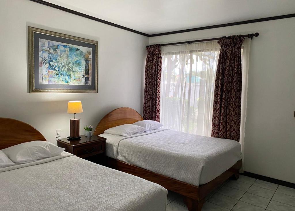 阿拉胡埃拉Brillasol Airport Hotel的一间卧室设有两张床和窗户。