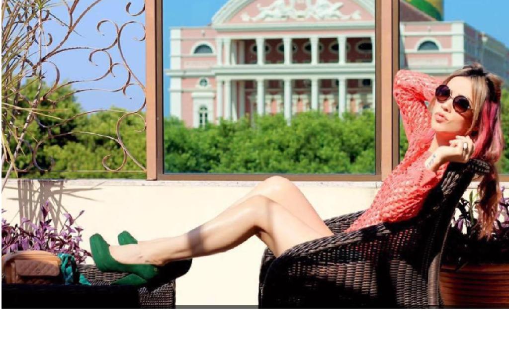 马瑙斯卡萨希尔托精品酒店的坐在窗子椅子上的女人