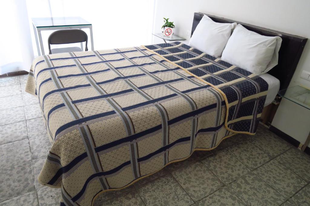 阿瓜斯卡连特斯HOTEL LLANITO AGS的一张床上,床上有毯子,椅子放在房间里
