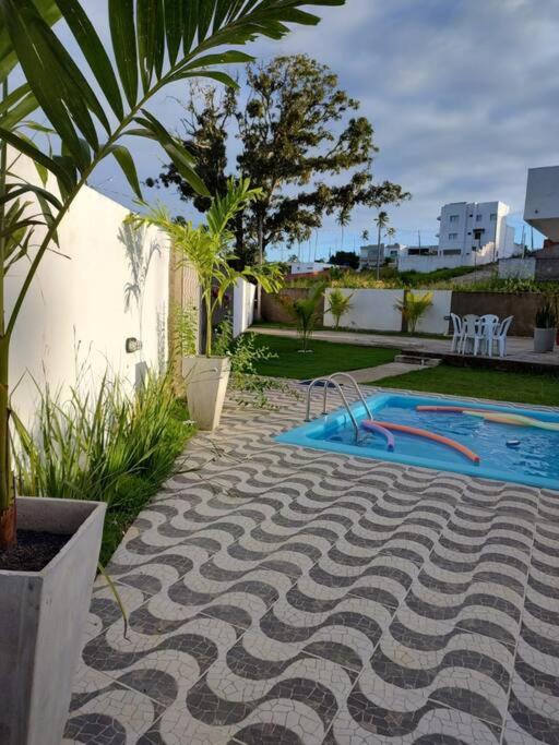 帕里普埃拉Casa de Praia em Condomínio Fechado em Alagoas!的棕榈树庭院中的游泳池