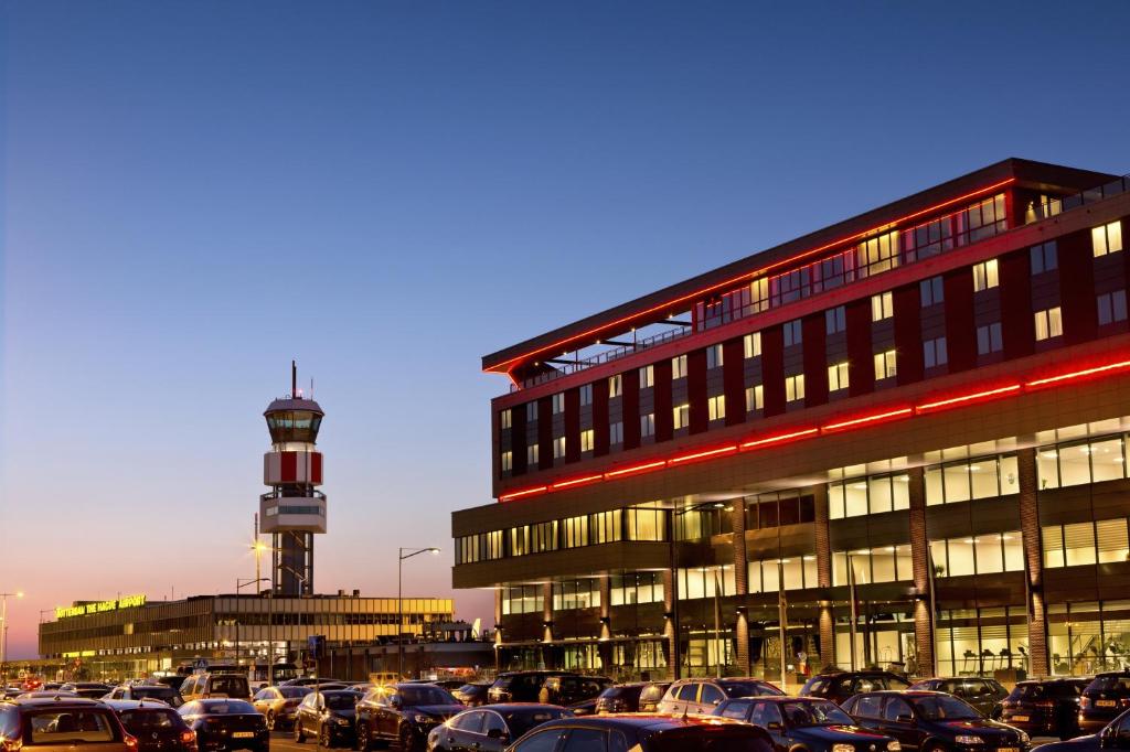 鹿特丹Fletcher Hotel-Restaurant Wings-Rotterdam的灯塔前停有车辆的停车场