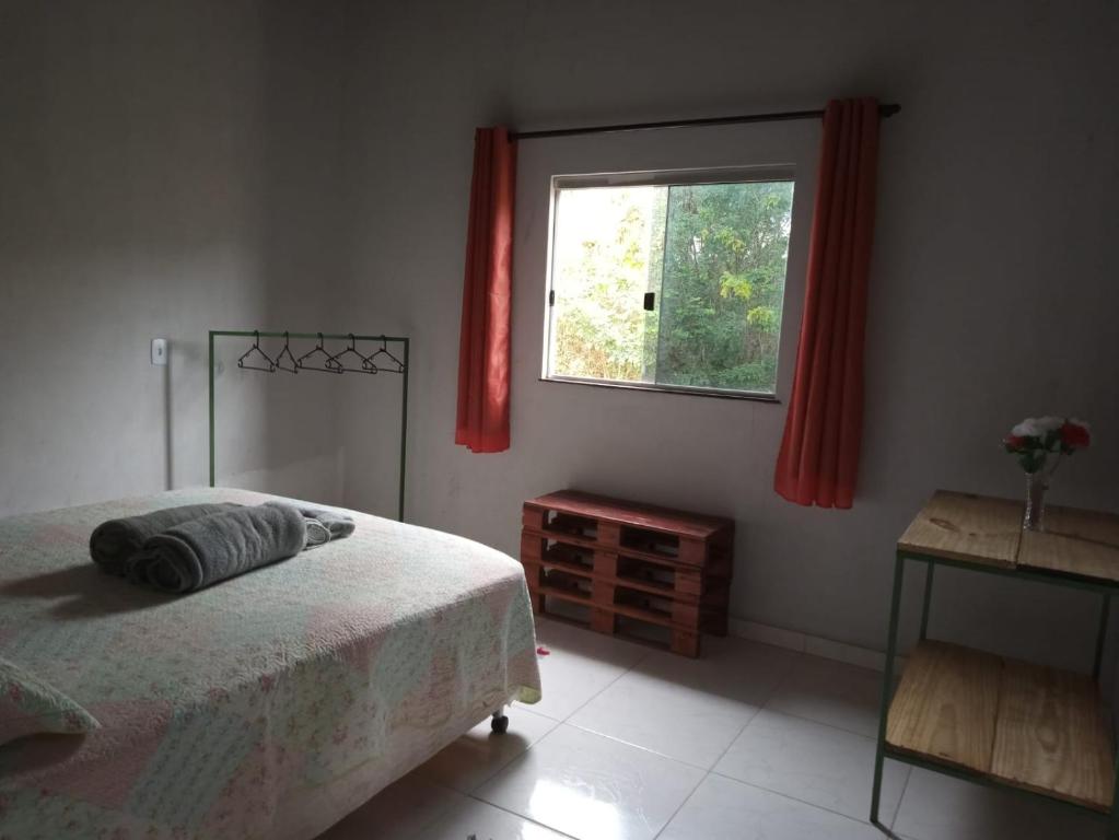 卡瓦坎特CASA TEMPORADA DONA CECÍLIA的一间卧室配有床和红色窗帘的窗户