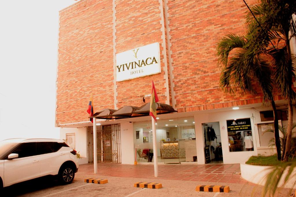 巴兰基亚Hotel Yivinaca的停在砖楼前的白色汽车