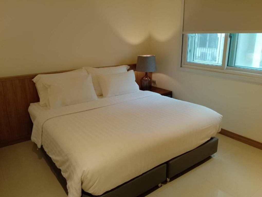 芭堤雅市中心芭堤雅西山酒店的卧室内的一张大白色床,带有窗户