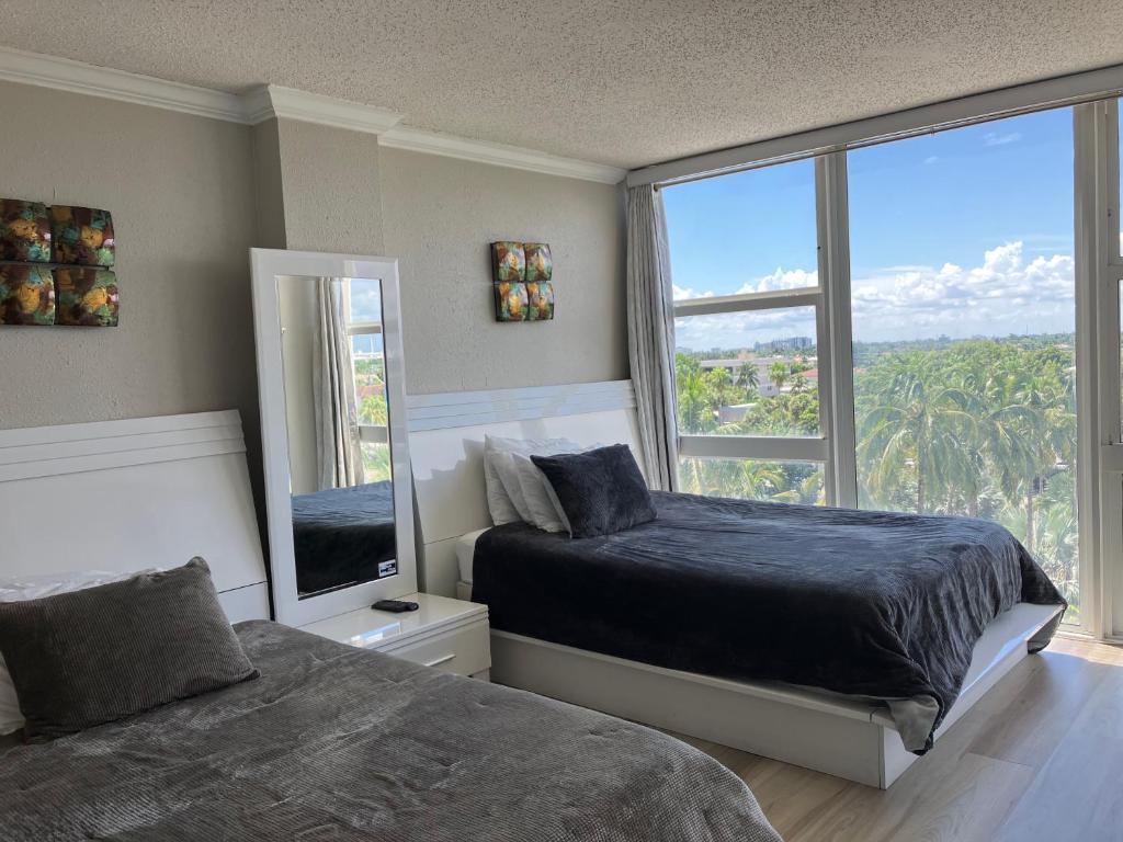 劳德代尔堡Oceanview on BEACH Fort Lauderdale located in resort, large 2 bedroom corner unit partial ocean view的一间卧室设有两张床和大窗户