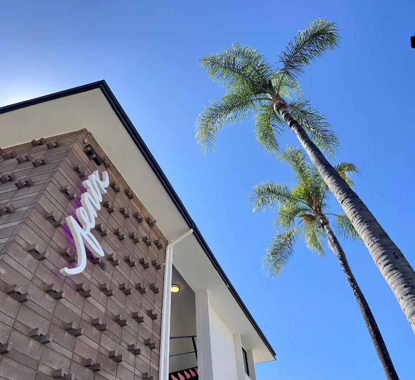洛杉矶Fenix Hotel Hollywood的棕榈树旁的一座建筑,上面有恐龙标志