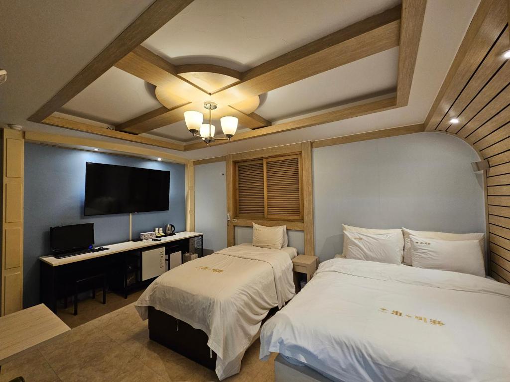 大田Hotel G7 Daejeon的一间卧室配有两张床、一张桌子和一台电视。