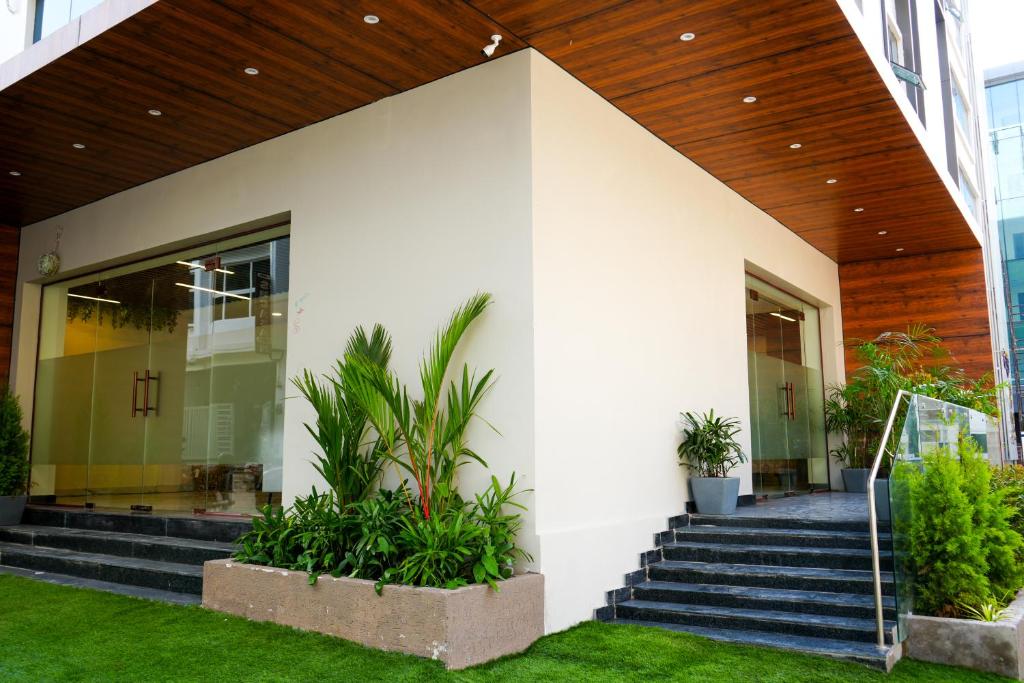 海得拉巴Casa Hotel & Suites, Gachibowli, Hyderabad的白色的建筑,有楼梯和植物