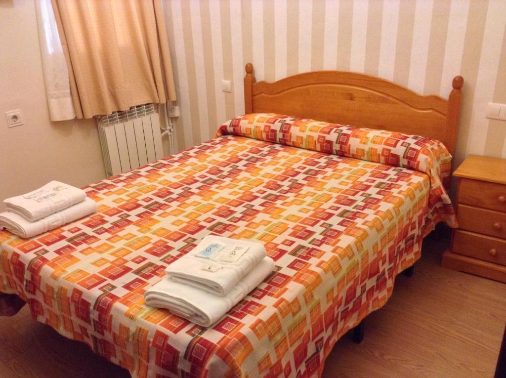 格拉纳达奇迹膳食公寓的一间卧室配有一张床,上面有两条毛巾