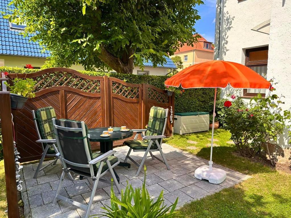萨斯尼茨Ferienwohnung Seerose的庭院配有桌椅和遮阳伞。