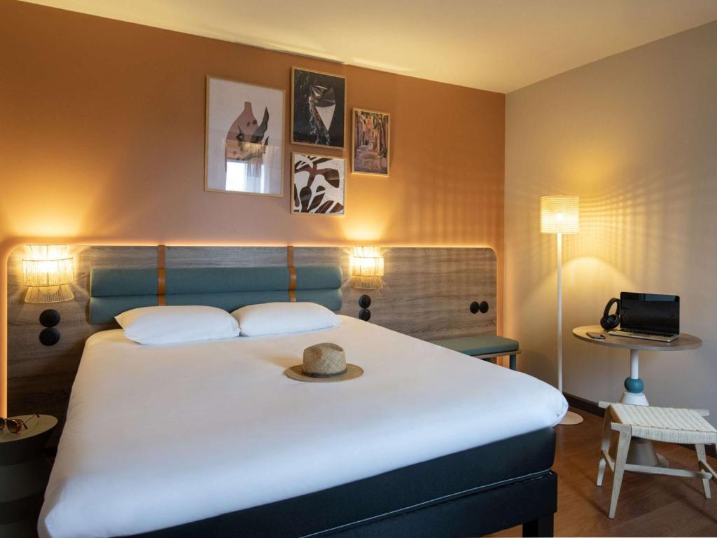 孔格林宜必思高尔夫圣特洛佩兹酒店的一间卧室配有一张大床,上面有帽子