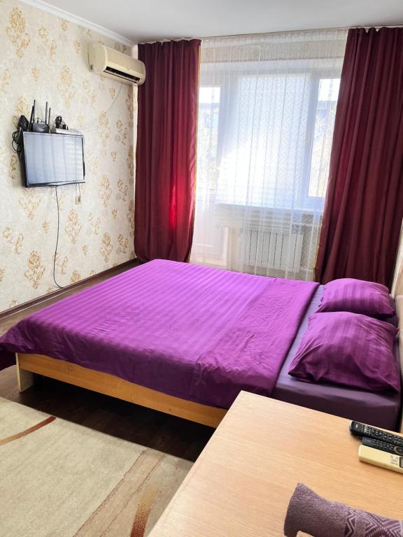 阿特劳Однокомнатная квартира в Жилгородке рядом с ДостарМед的带窗户的客房内的紫色床