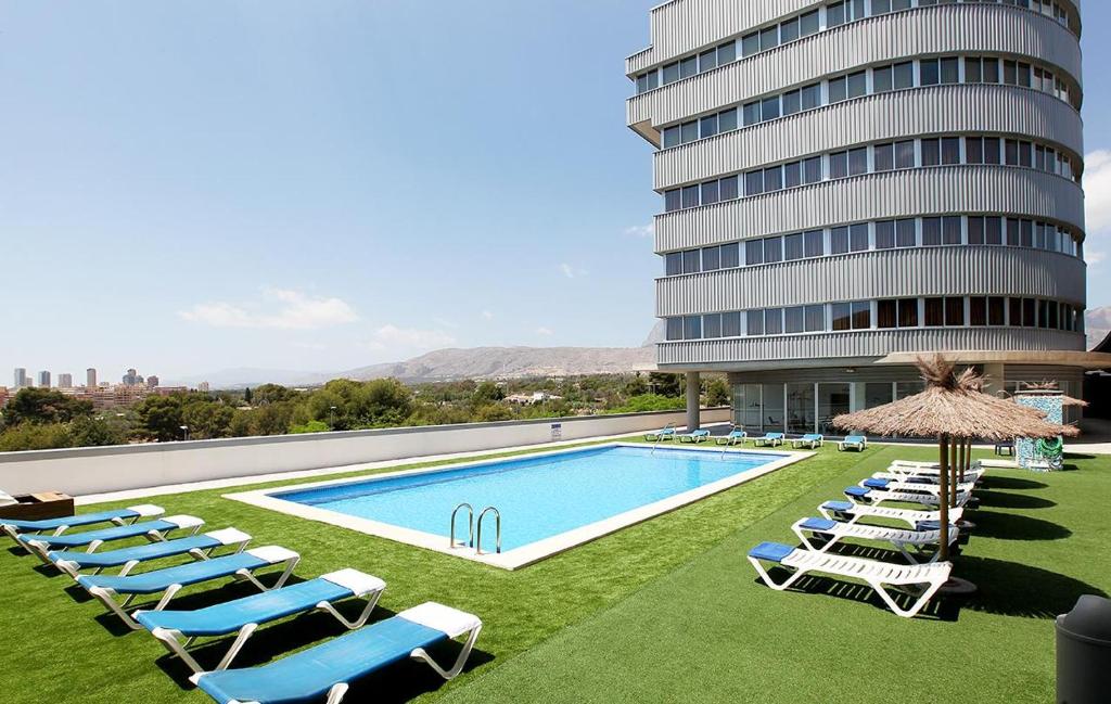 贝尼多姆拉艾斯塔西昂酒店的一座带躺椅的游泳池和一座建筑