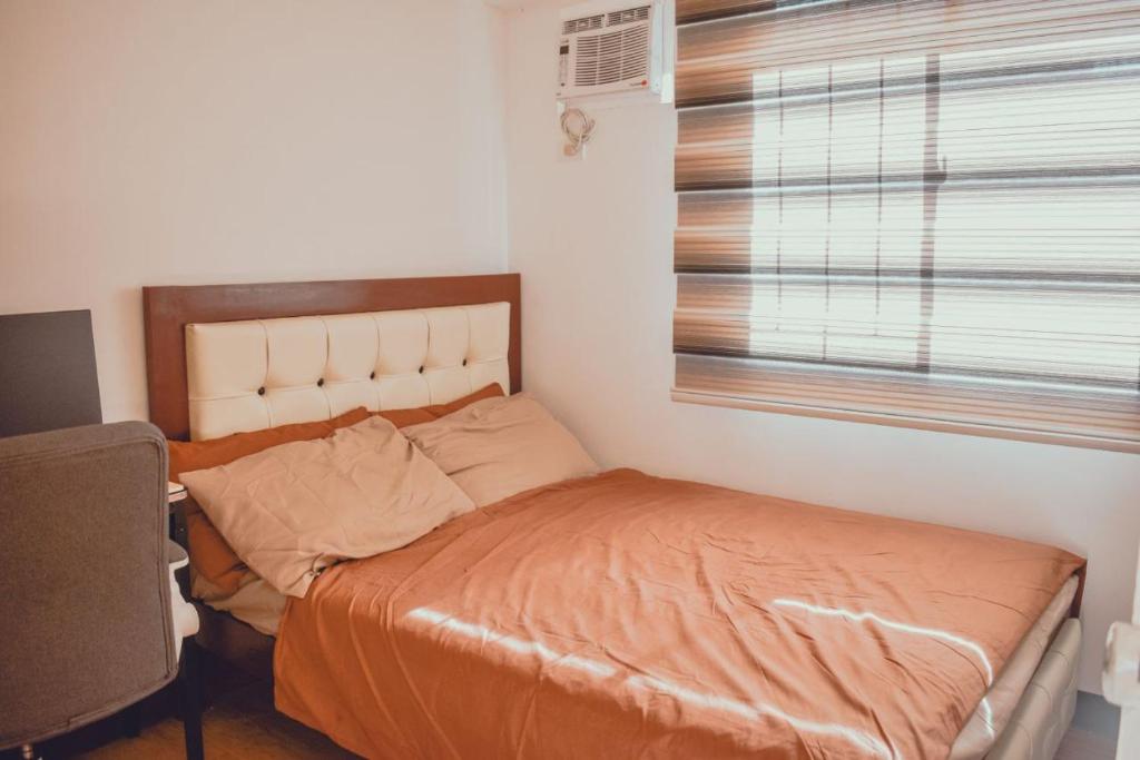 达沃市AiPad Condo Rentals的一间卧室配有一张带橙色棉被的床和窗户