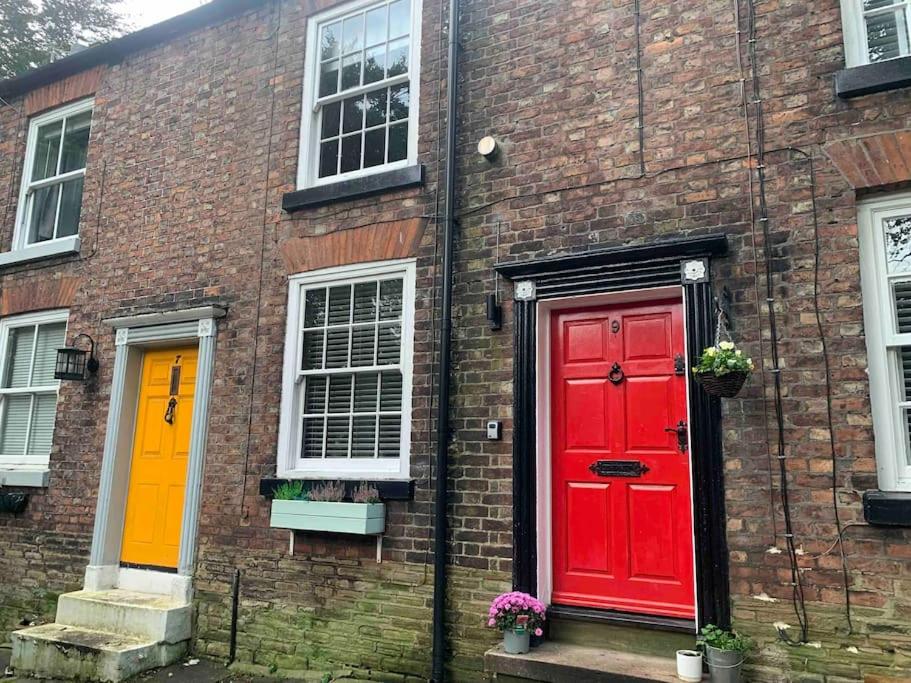 麦克尔斯菲尔德Cosy Cottage (Free parking)的砖砌建筑,设有两个红色的门窗