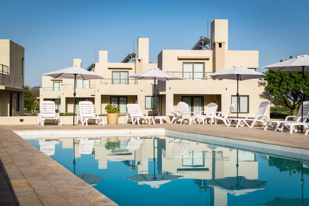 拉里奥哈Casa Adela - Cabañas Resort的一个带游泳池、椅子和遮阳伞的度假村