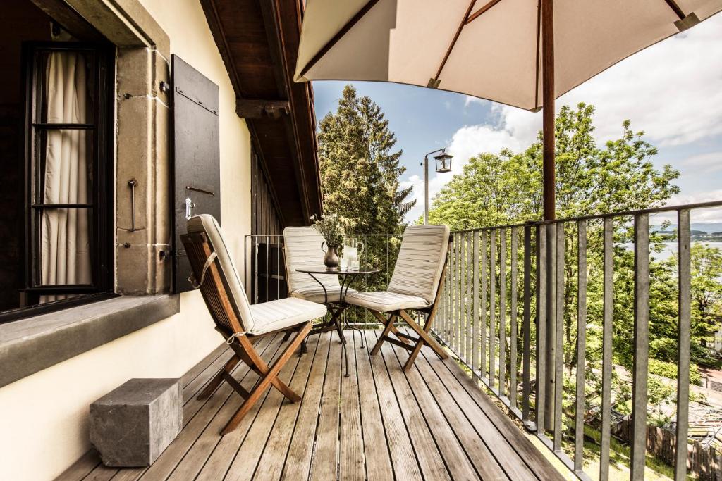 穆尔滕La Pinte du Vieux Manoir的阳台配有两把椅子、一张桌子和一把伞