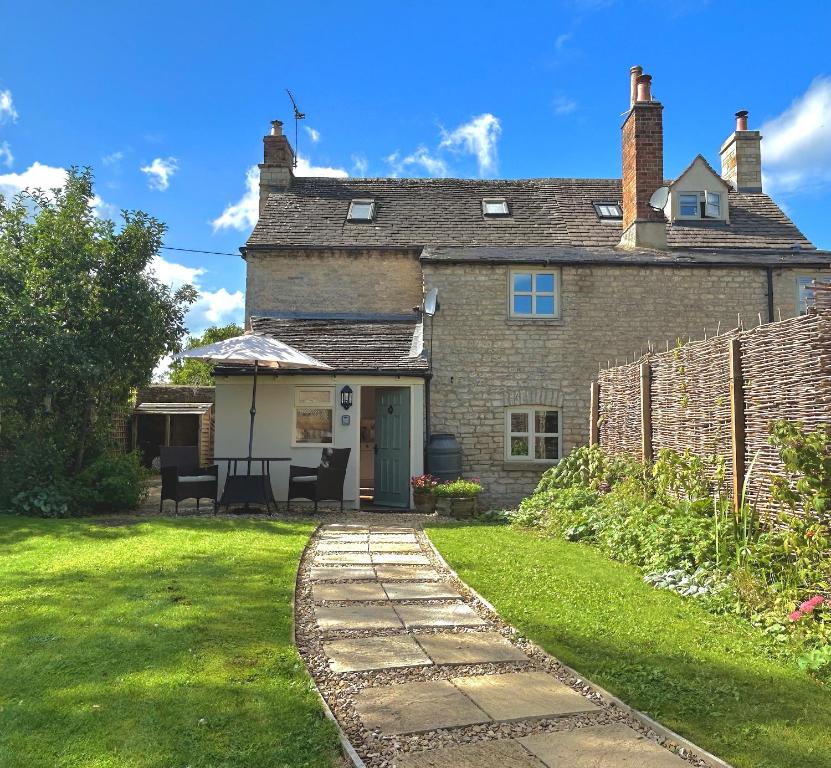 QueningtonCosy Cotswold Cottage with garden Quenington near Bibury的一座带庭院和草地的老砖屋