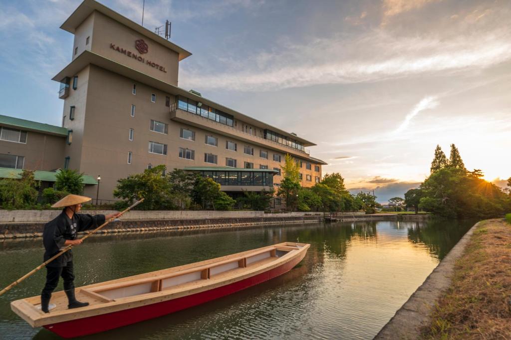 柳川KAMENOI HOTEL Yanagawa的正在河里划船的人