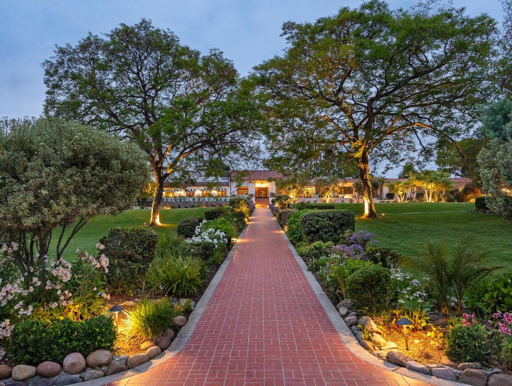 兰乔圣达菲The Inn at Rancho Santa Fe的花园中种满树木和鲜花的砖路