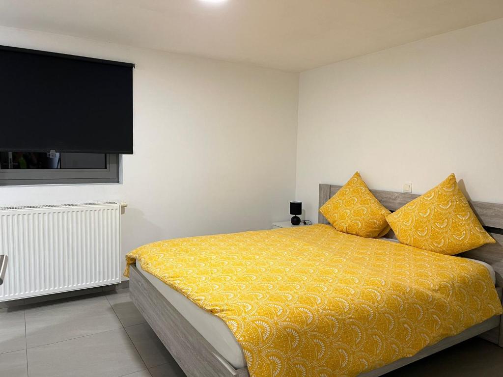 鲁瑟拉勒Alexa Residence - Appartement 1的一间卧室配有一张带黄床单的床和一台平面电视。