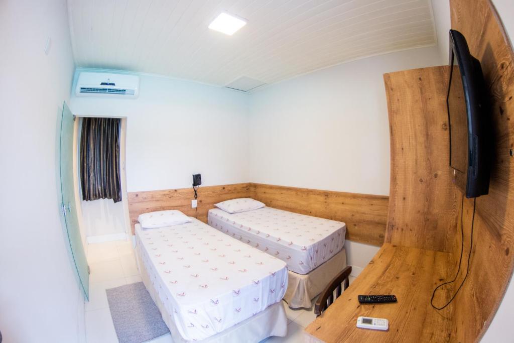 伊塔布纳Pousada Veneza的客房设有两张床和一台平面电视。