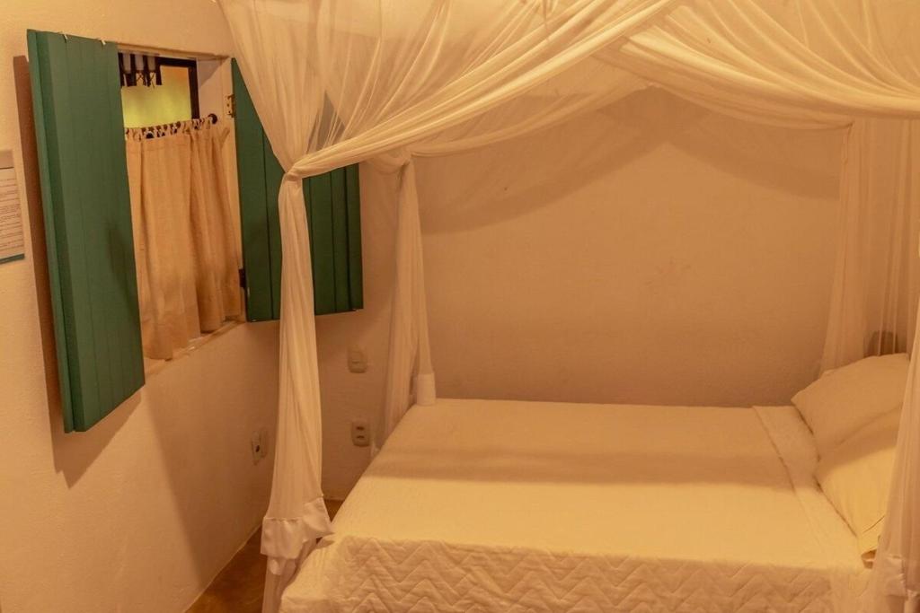 塞古罗港Suites da Loja Caraíva的一间卧室配有一张带天蓬的白色床