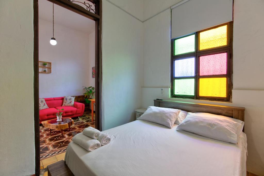 卡利Casa Blanca San Antonio Hostal Boutique的卧室配有白色的床和红色沙发