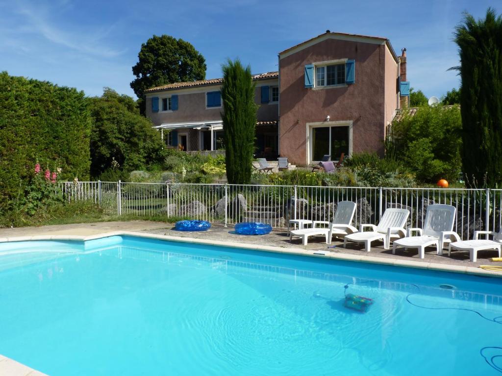 SaillansLa Maison Rose的一个带椅子的游泳池和一个背景房子