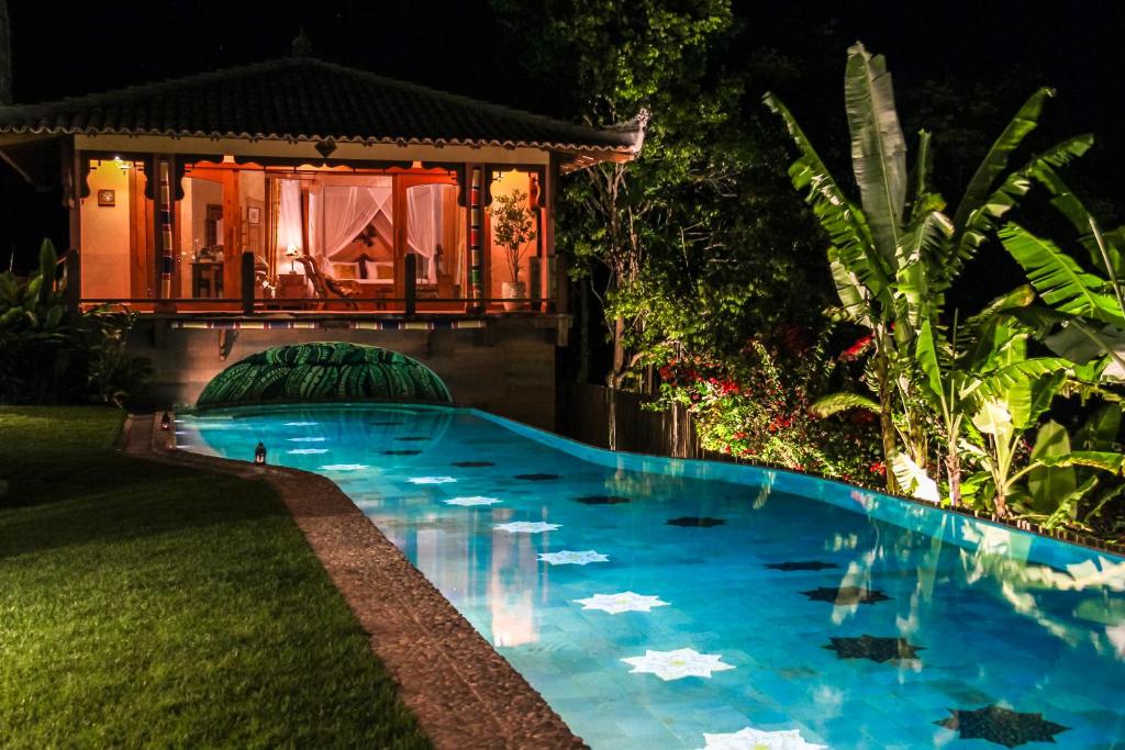 阿拉亚尔达茹达Sagui Boutique Hotel的夜间在房子前面的游泳池