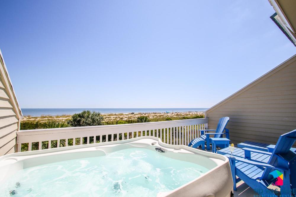 泰比岛Beachfront Oasis At Tybee Island的一个带椅子和海滩的阳台的热水浴池