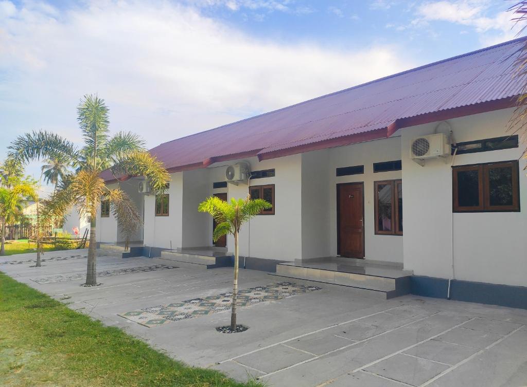 DondoHome Syariah Guest House Ampana的白色的小建筑,有紫色的屋顶